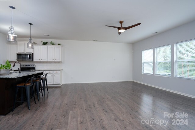 unfurnished living room featuring ceiling fan and dark hardwood / wood-style flooring