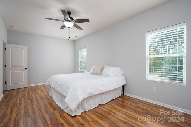 bedroom featuring ceiling fan, dark wood-type flooring, and multiple windows