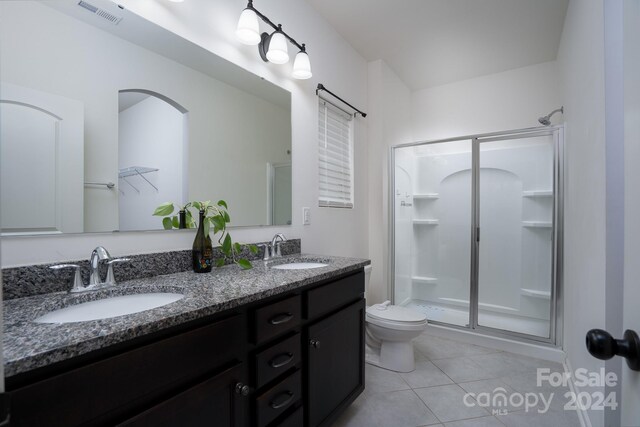 bathroom with tile patterned flooring, vanity, toilet, and a shower with shower door