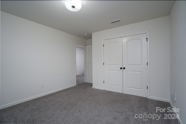 unfurnished bedroom featuring a closet and dark colored carpet