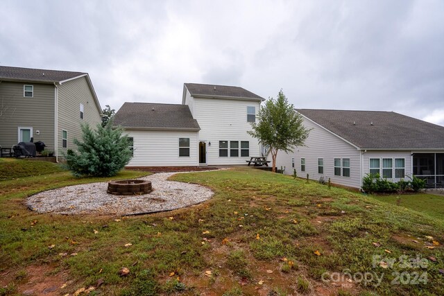 rear view of house featuring a fire pit and a lawn