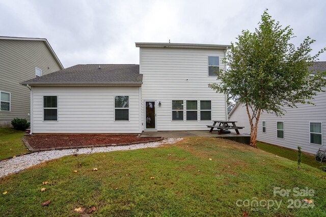 rear view of property featuring a lawn and a patio area