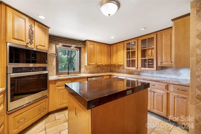 kitchen featuring tasteful backsplash, a kitchen island, stainless steel appliances, dark stone counters, and sink