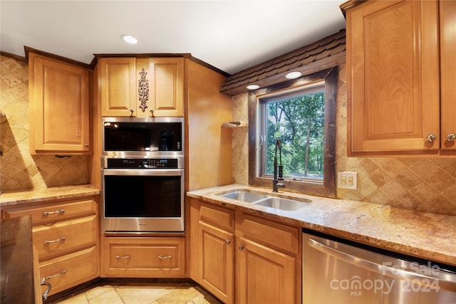 kitchen with light stone countertops, stainless steel appliances, tasteful backsplash, and sink