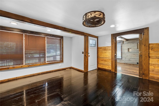 spare room featuring wood walls and dark hardwood / wood-style flooring