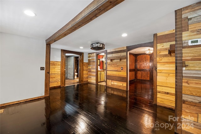 spare room featuring beam ceiling, wooden walls, and hardwood / wood-style floors