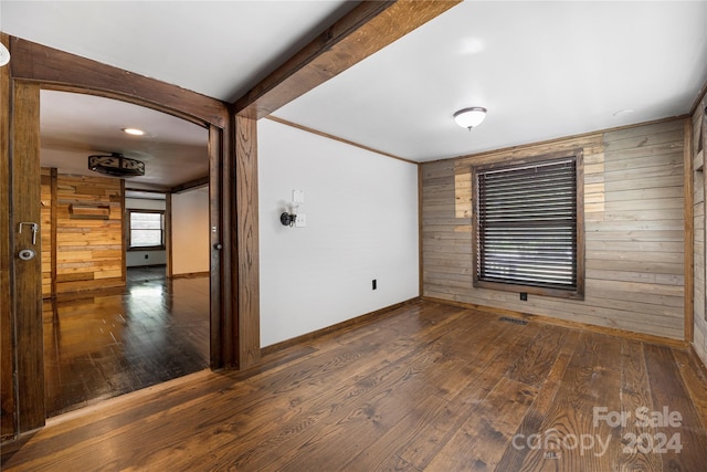 unfurnished room with wood walls and dark hardwood / wood-style flooring