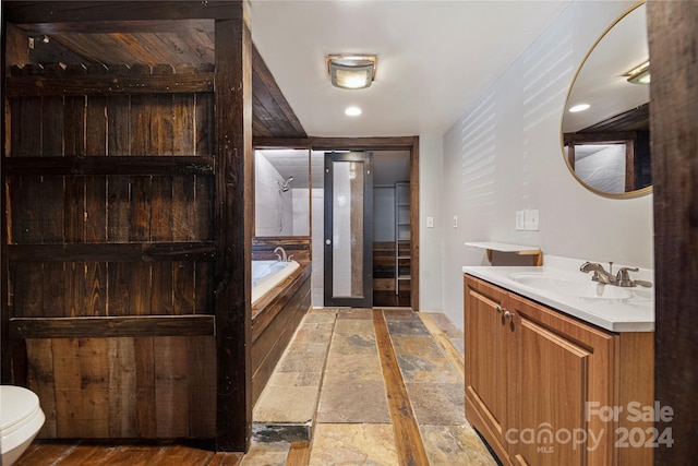 bathroom featuring vanity, a tub to relax in, and toilet