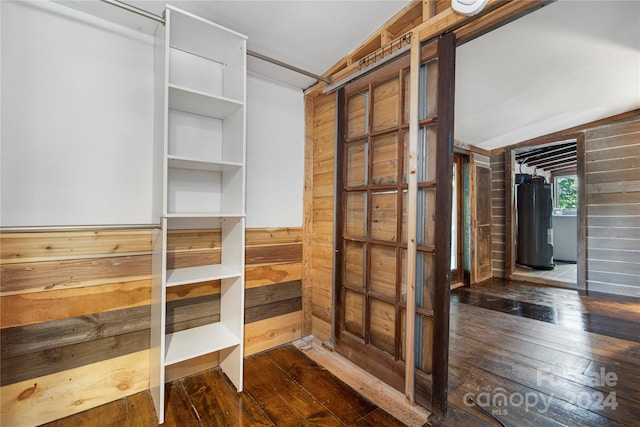 interior space featuring a barn door, water heater, vaulted ceiling, and dark hardwood / wood-style floors