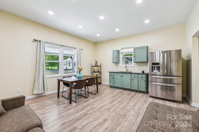 kitchen featuring green cabinetry, light wood-type flooring, stainless steel fridge with ice dispenser, and a healthy amount of sunlight