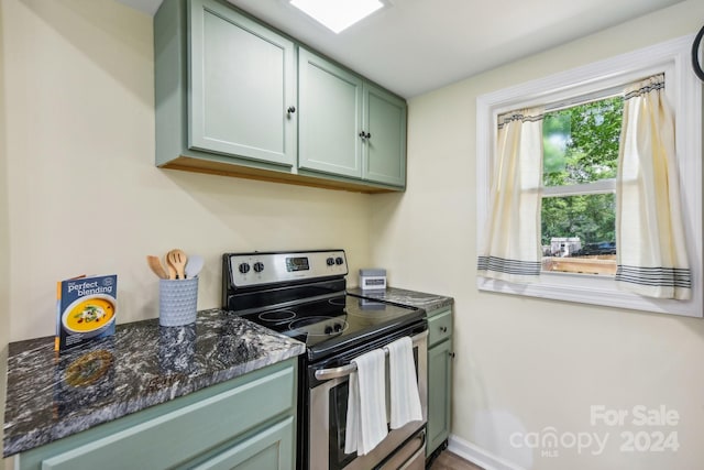 kitchen featuring green cabinets, dark stone countertops, and stainless steel electric range