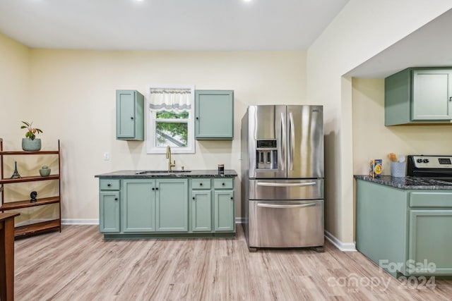 kitchen featuring stainless steel refrigerator with ice dispenser, light hardwood / wood-style floors, sink, and green cabinets