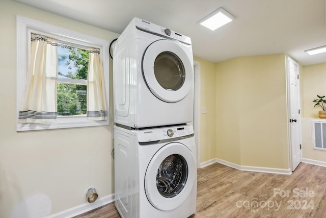 laundry area with stacked washer / dryer and light hardwood / wood-style floors