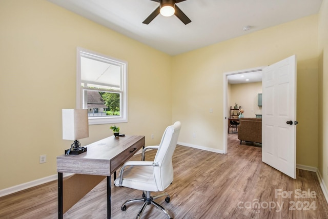 home office with light hardwood / wood-style flooring and ceiling fan