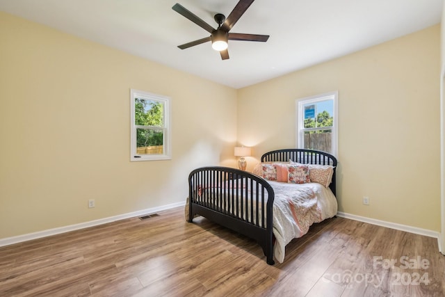 bedroom with multiple windows, hardwood / wood-style floors, and ceiling fan