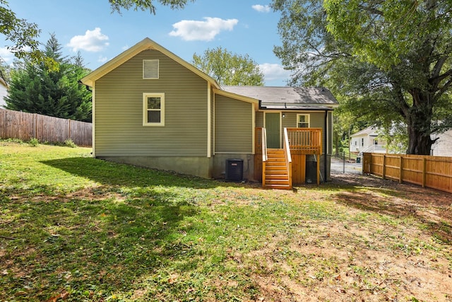 rear view of property with central AC and a yard