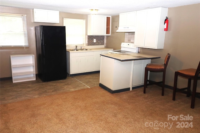 kitchen with black fridge, kitchen peninsula, white cabinetry, ventilation hood, and white range