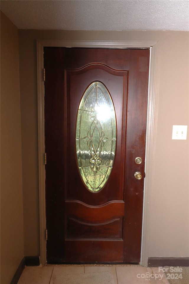 foyer with a textured ceiling and light tile patterned floors