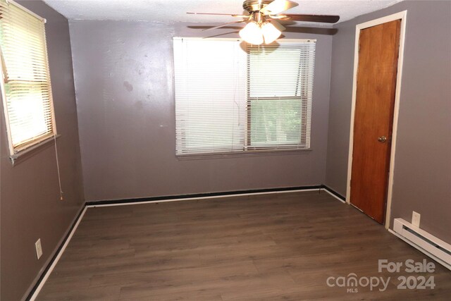 unfurnished room featuring baseboard heating, dark hardwood / wood-style floors, and ceiling fan