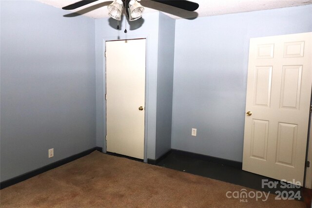 spare room with dark carpet and ceiling fan