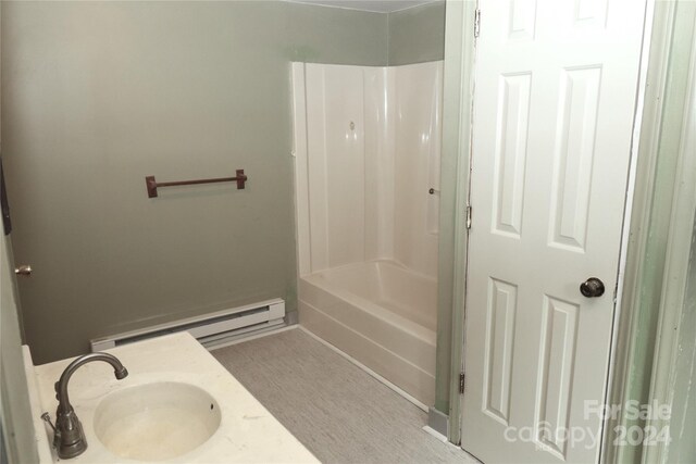 bathroom featuring sink, a baseboard heating unit, and  shower combination