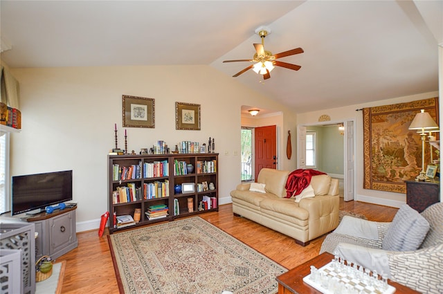 living room featuring ceiling fan, light hardwood / wood-style flooring, and vaulted ceiling