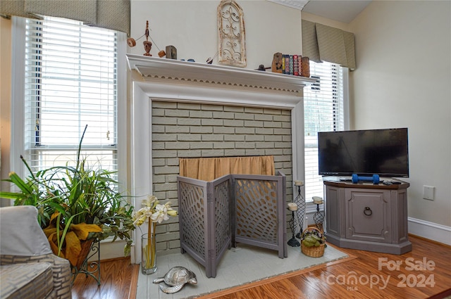 living room featuring a brick fireplace and hardwood / wood-style flooring