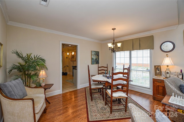 dining room featuring a notable chandelier, ornamental molding, and hardwood / wood-style flooring