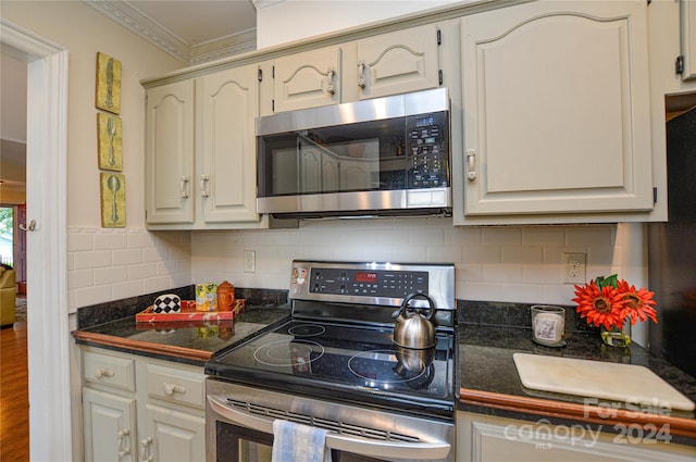 kitchen with ornamental molding, white cabinetry, hardwood / wood-style flooring, stainless steel appliances, and decorative backsplash