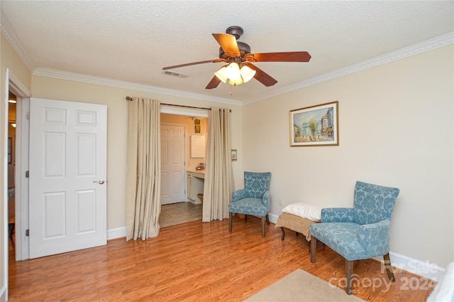 sitting room with ceiling fan, a textured ceiling, crown molding, and light hardwood / wood-style floors