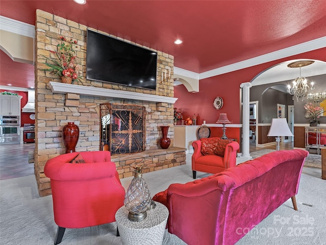 carpeted living room with a chandelier and a stone fireplace