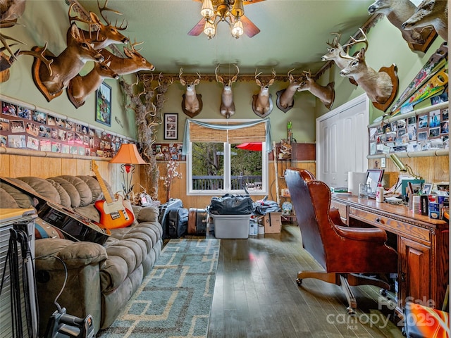 office area featuring ceiling fan, dark hardwood / wood-style flooring, and wood walls