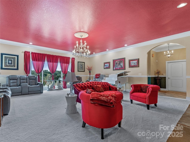 living area with arched walkways, ornamental molding, a textured ceiling, carpet flooring, and a chandelier