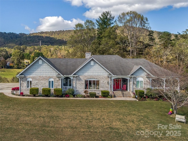 view of front of home featuring a forest view, a chimney, and a front lawn