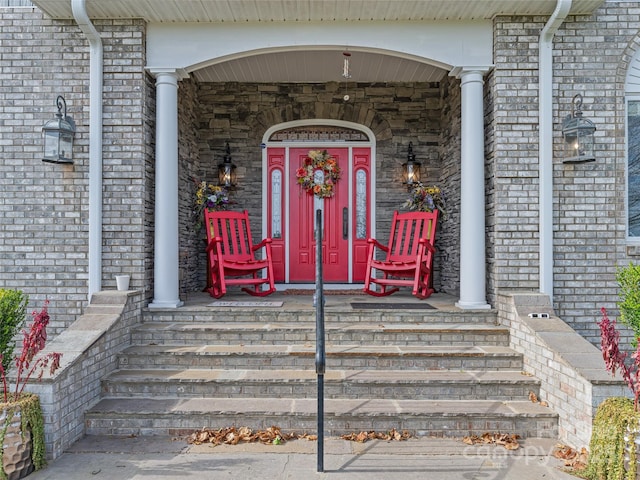 doorway to property featuring covered porch and brick siding