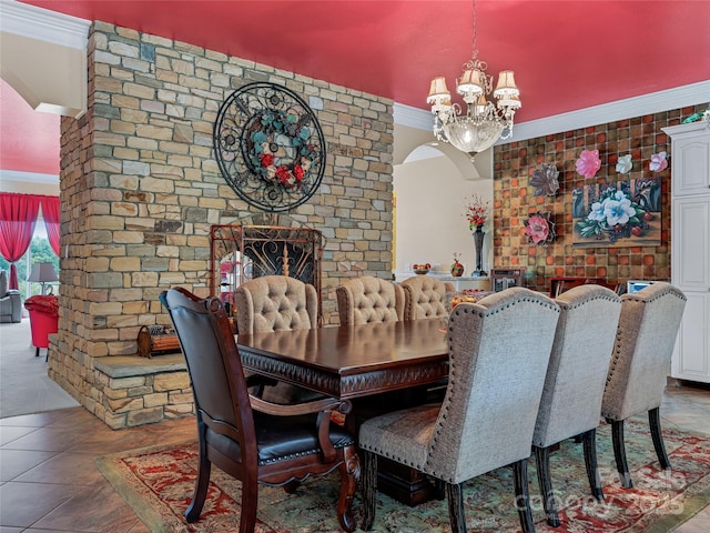 tiled dining space featuring ornamental molding, arched walkways, a notable chandelier, and a fireplace