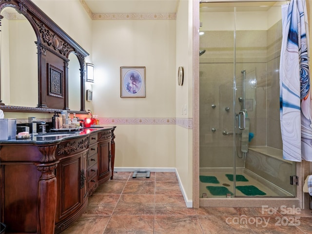 full bath with a stall shower, vanity, and baseboards