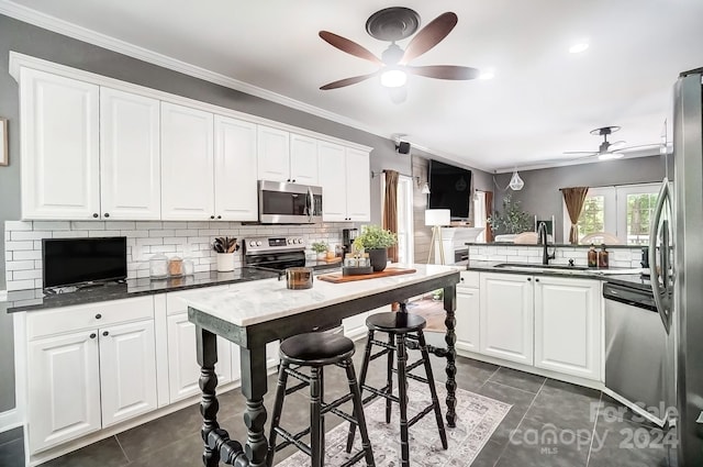 kitchen featuring white cabinets, ornamental molding, stainless steel appliances, and sink