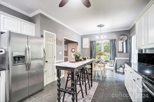 kitchen featuring dark tile patterned floors, white cabinets, appliances with stainless steel finishes, decorative light fixtures, and crown molding