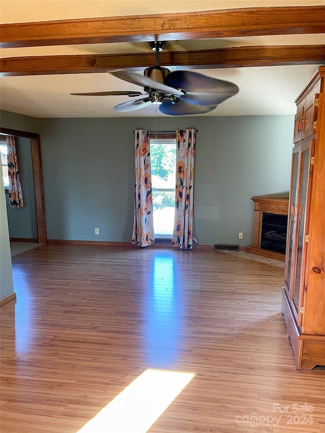 interior space featuring ceiling fan, a textured ceiling, light wood-type flooring, and beam ceiling