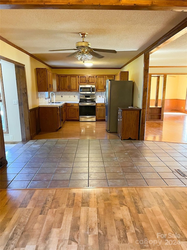 1610 Sierra Rd, York, SC 29745 - kitchen with light wood-style flooring, a sink, appliances with stainless steel finishes, brown cabinetry, and ornamental molding