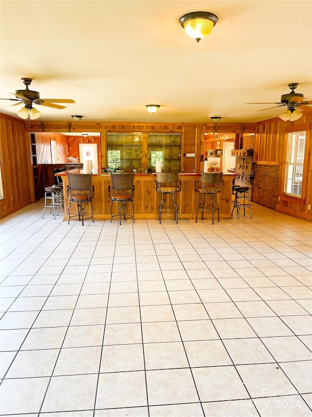 kitchen featuring wood walls, ceiling fan, and light tile patterned flooring