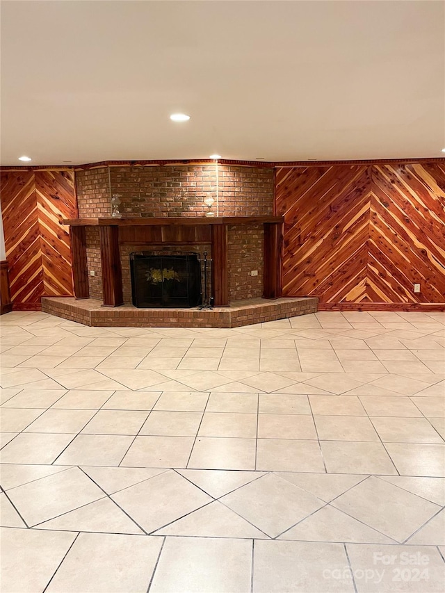 unfurnished living room with a fireplace and wooden walls