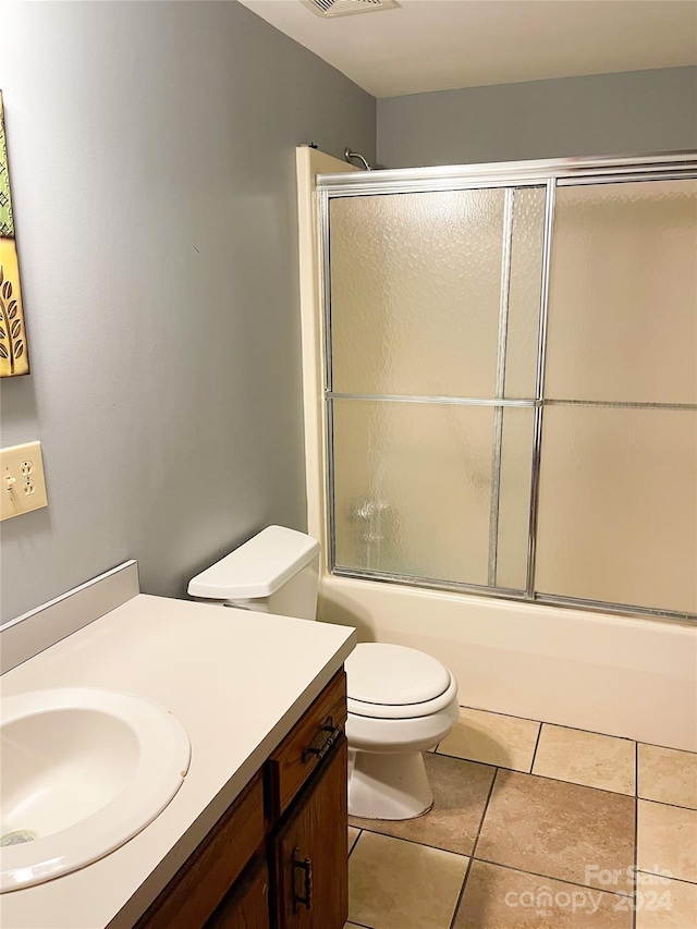 full bathroom featuring tile patterned flooring, shower / bath combination with glass door, toilet, and vanity