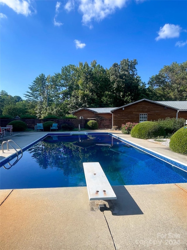 view of swimming pool with a diving board and a patio