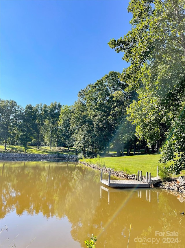 dock area with a lawn and a water view