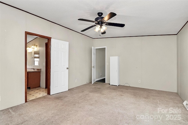 unfurnished bedroom featuring ensuite bathroom, ceiling fan, light colored carpet, and a textured ceiling