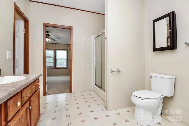 bathroom featuring vanity, a shower with door, toilet, and ceiling fan