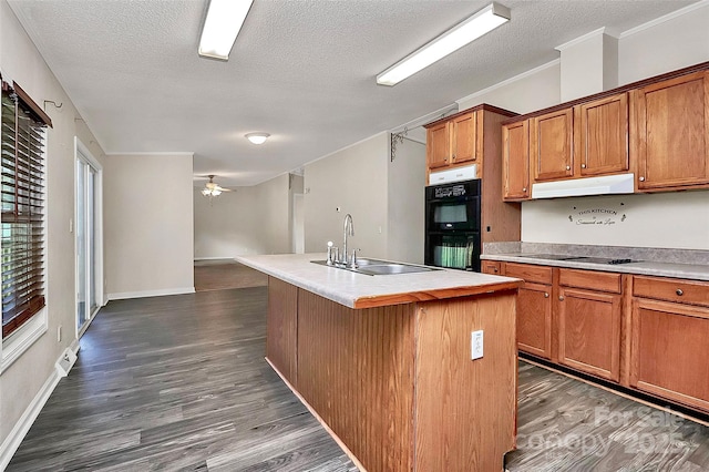 kitchen with a textured ceiling, ventilation hood, a kitchen island with sink, sink, and black appliances