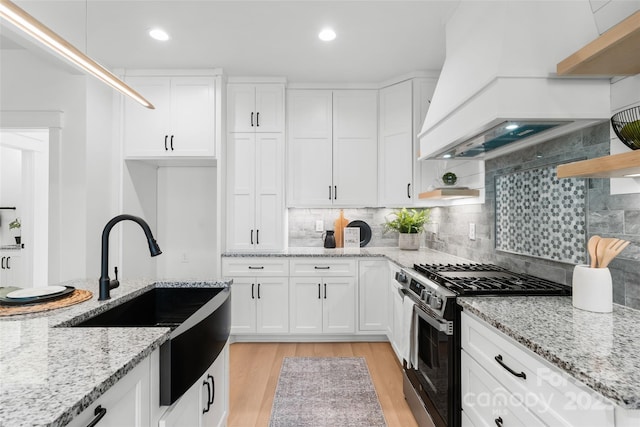 kitchen featuring white cabinetry, premium range hood, and stainless steel range with gas stovetop